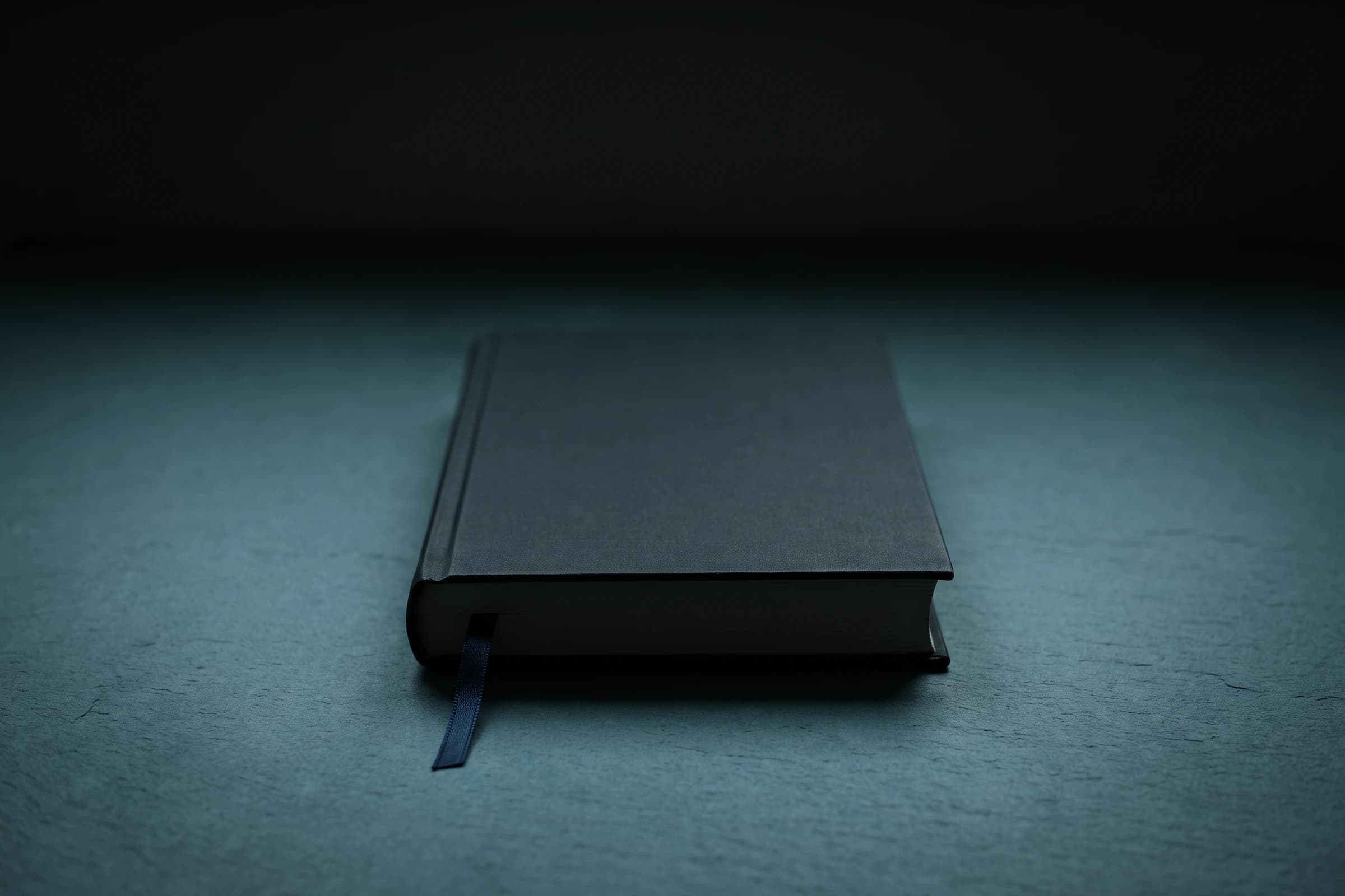 Ein geschlossenes Buch ohne Aufdruck mit heraushängendem Lesebändchen auf dunklem Grund