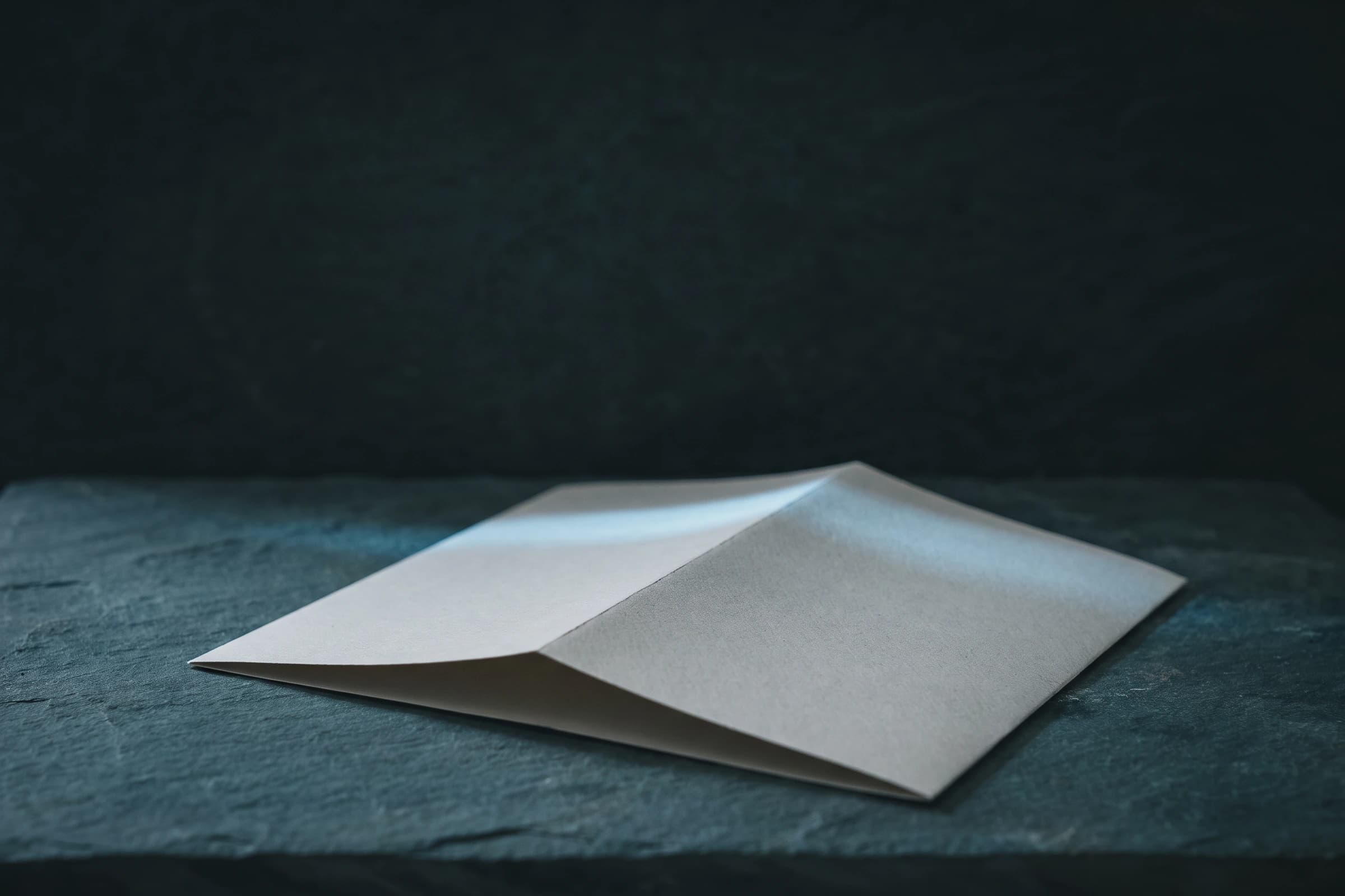 Ein einmal gefaltetes leeres Blatt Papier, ein schmales Lichtband über dem Knick
